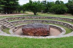 a large rock sitting in the middle of a circular stone area with steps leading up to it