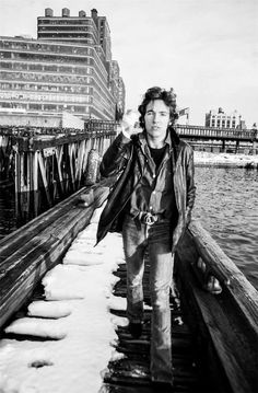 black and white photograph of a man standing on a pier