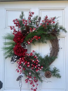 a wreath with pine cones and berries hanging on a door