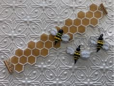 three bees sitting on top of a piece of white fabric with yellow and black designs