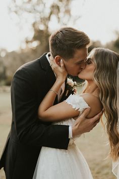 a bride and groom kissing each other outside