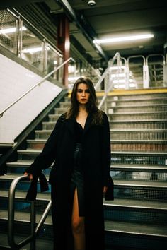 a woman standing in front of an escalator with her hand on her hip