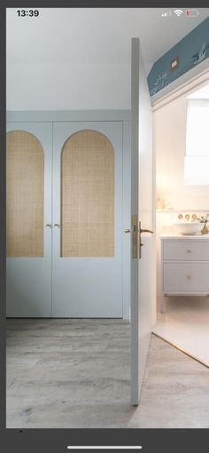 an open door leading to a bathroom with white walls and wood flooring on the side