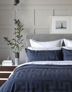 a bed with blue and white comforter in a bedroom next to a plant on a nightstand