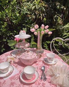 a pink table set with dishes and cups