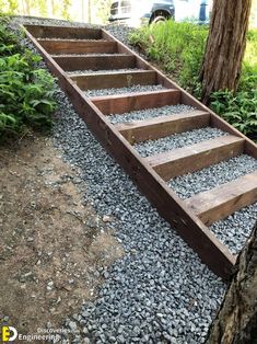 the steps are made out of wood and gravel in front of a tree with green plants