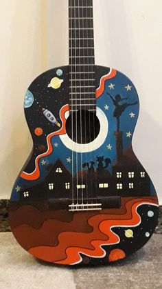 an acoustic guitar painted with the theme of outer space and stars on it's body