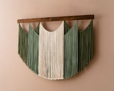 a green and white wall hanging on the side of a pink wall with wooden frame