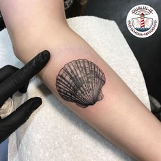 a small tattoo on the arm of a woman with a seashell in it's shell