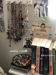 there are many necklaces hanging on the wall next to books and a toy bear