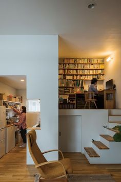 there is a person standing in the kitchen next to some bookshelves and stairs