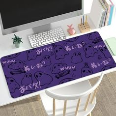 a computer desk topped with a purple mouse pad covered in cartoon character faces and letters