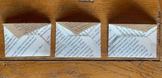 three pieces of folded paper sitting on top of a wooden table