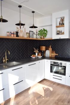 a kitchen with white cabinets and black backsplash tiles on the wall above the sink