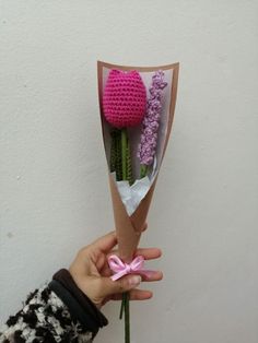 a person holding a bouquet of flowers in their left hand with a pink ribbon tied around it