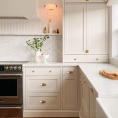 a kitchen with white cabinets and gold pulls on the drawers, an oven in the center