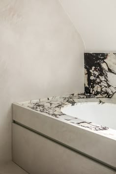 a bath tub sitting next to a white wall with black and white designs on it