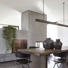 a dining room table with chairs and vases on it in front of a fireplace