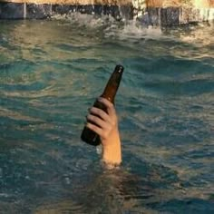 a person holding a beer bottle in the water