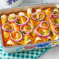 a casserole dish with onions, cheese and meat in it on a table