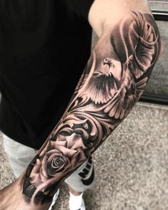 a man with a black and white tattoo on his arm is holding a rose in front of him