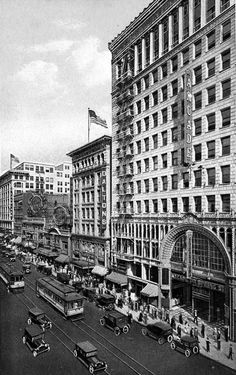 an old black and white photo of cars driving down the street in front of buildings