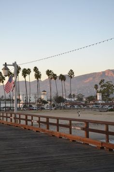 a wooden pier with palm trees and mountains in the background