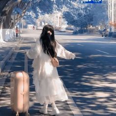 a woman with long black hair is standing on the street and pulling her suitcase behind her