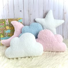 three stars and clouds are sitting on a fluffy white surface next to a pillow with a book