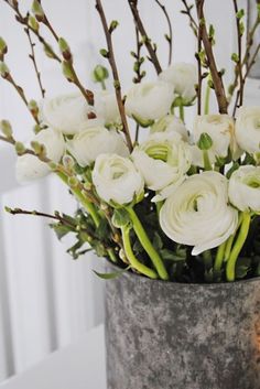 a vase filled with white flowers sitting on top of a table next to a candle