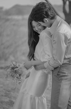 black and white photograph of a couple holding each other in front of an open field