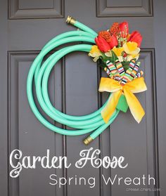 a green hose attached to a door with flowers in it and a yellow bow on the front