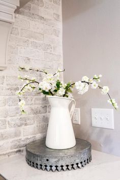 a white vase filled with flowers sitting on top of a counter