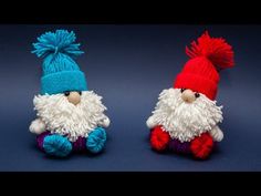 two knitted gnomes sitting next to each other on a blue surface with one wearing a red and white hat