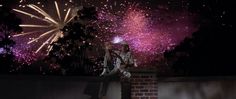 a man standing on top of a brick wall next to fireworks