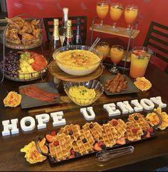 a table topped with waffles, fruit and other foods next to glasses of orange juice