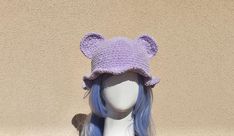 a white mannequin head wearing a purple crocheted bear hat with ears