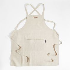 a white apron with an embroidered name on the front, and two zippers at the back