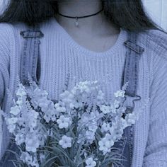 a woman wearing overalls holding a bouquet of flowers