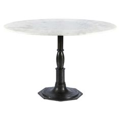 a white marble top dining table with black metal pedestals and an iron base, against a white background