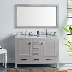 a bathroom vanity with two sinks and a mirror on the wall above it, in front of a window