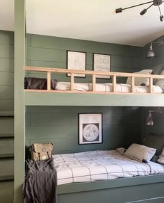 a bunk bed in a room with green walls and white sheets on the bottom floor