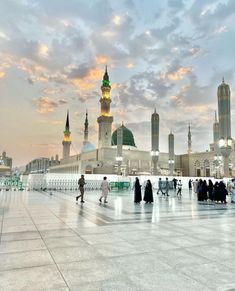 many people are walking around in the middle of a large courtyard with tall buildings behind them