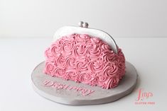 a cake shaped like a purse with pink frosting on the top and silver base