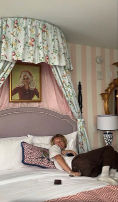 a woman laying on top of a bed next to a pink and white striped wall