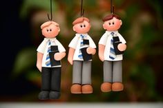 three small figurines hanging from strings in the shape of men with ties on their heads