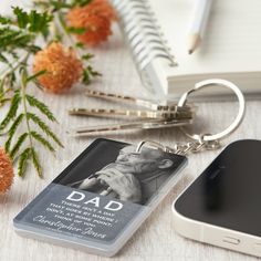 a cell phone sitting on top of a table next to a pen and keychain