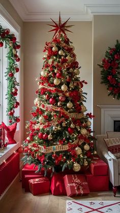 a decorated christmas tree in a living room with red and gold presents on the floor