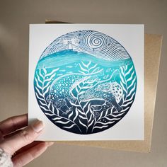 a hand holding up a card with an image of a whale in the ocean