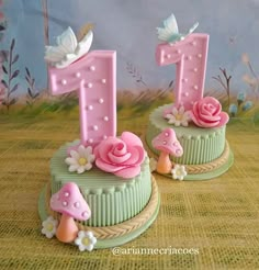 two birthday cakes with pink frosting and flowers on each one, sitting on a table